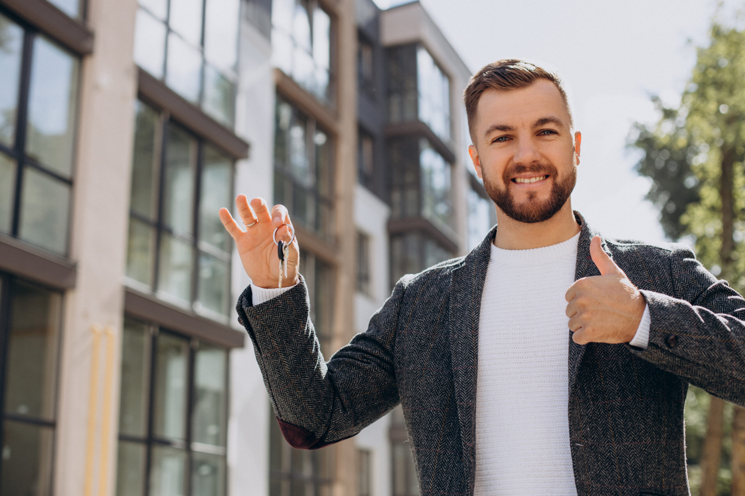 Jeune homme avec des clés devant son nouvel appartement